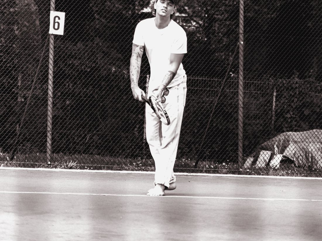 Adult man preparing to serve on an outdoor clay tennis court