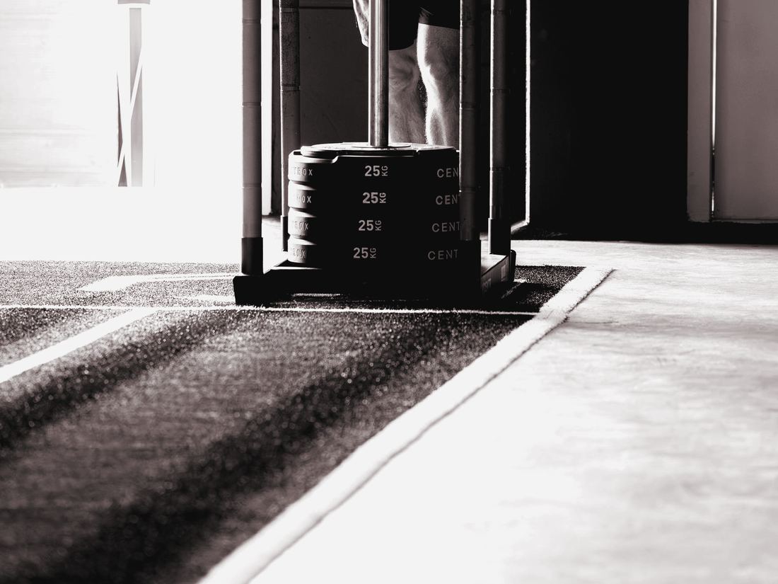 Adult man pushing a weighted sled across a gym floor