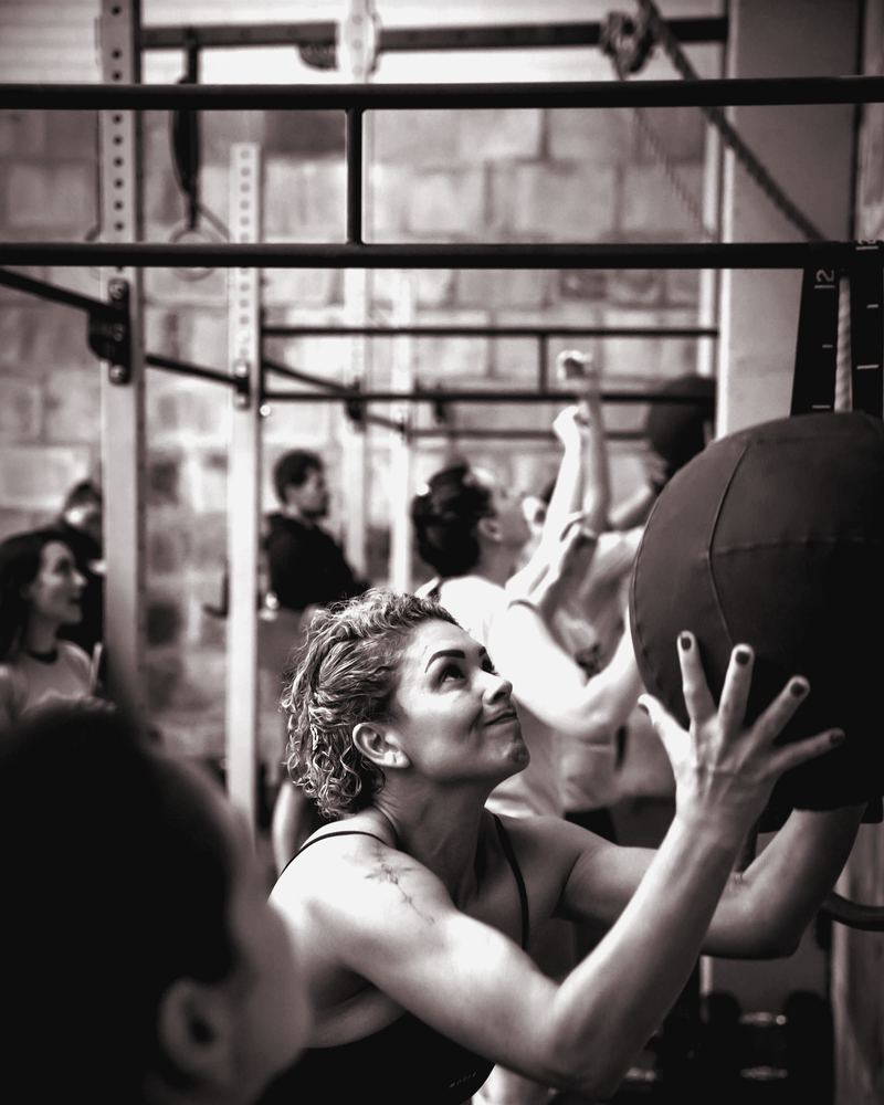 Adult athletes doing wall-ball throws in a group workout