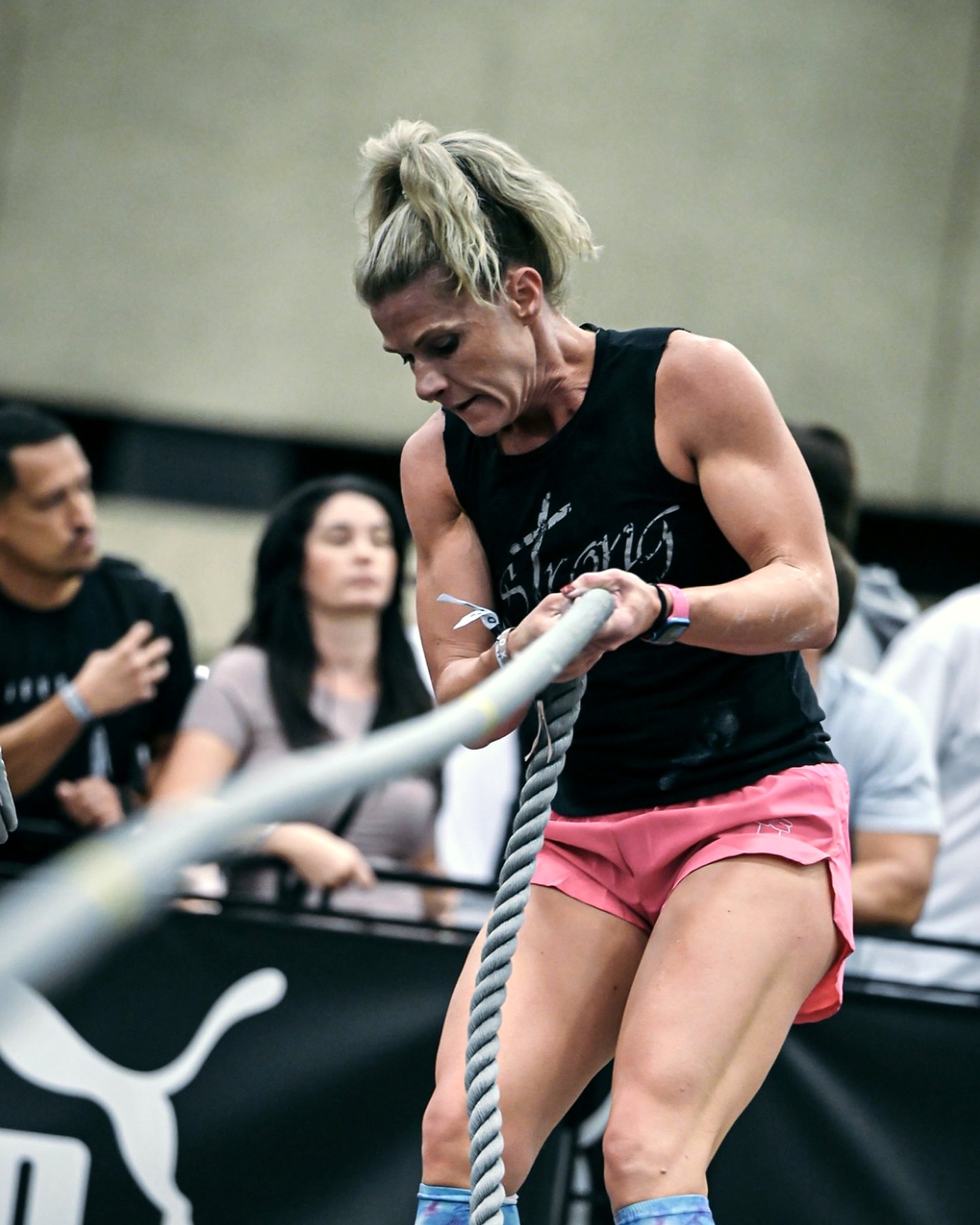 HYROX competitor hauling a sled pull rope hand over hand at a race