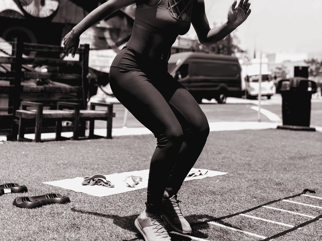 Adult woman doing agility-ladder footwork on turf