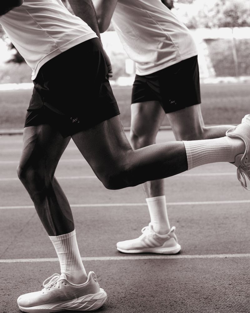 Two adult runners mid-stride on an athletics track
